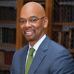 Dr. Herman Taylor, wearing a blue suit jacket, white shirt and green tie