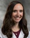 Jennifer L. Cohen, MD is facing the camera smiling and wearing a white lab coat, a maroon blouse and gold necklace. She also has long brown hair. 