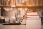 laptop next to a stack of books