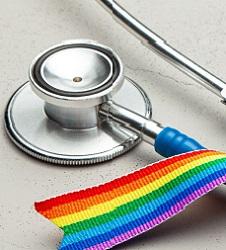 A stethoscope on a table with a rainbow ribbon around it